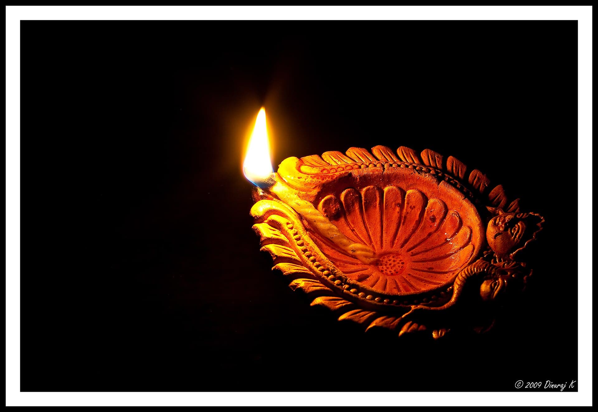 Rows of lit clay oil lamps (diyas) glowing for Diwali